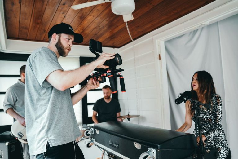 Equipo de producción filmando un videoclip musical con cámara cinematográfica y banda en vivo